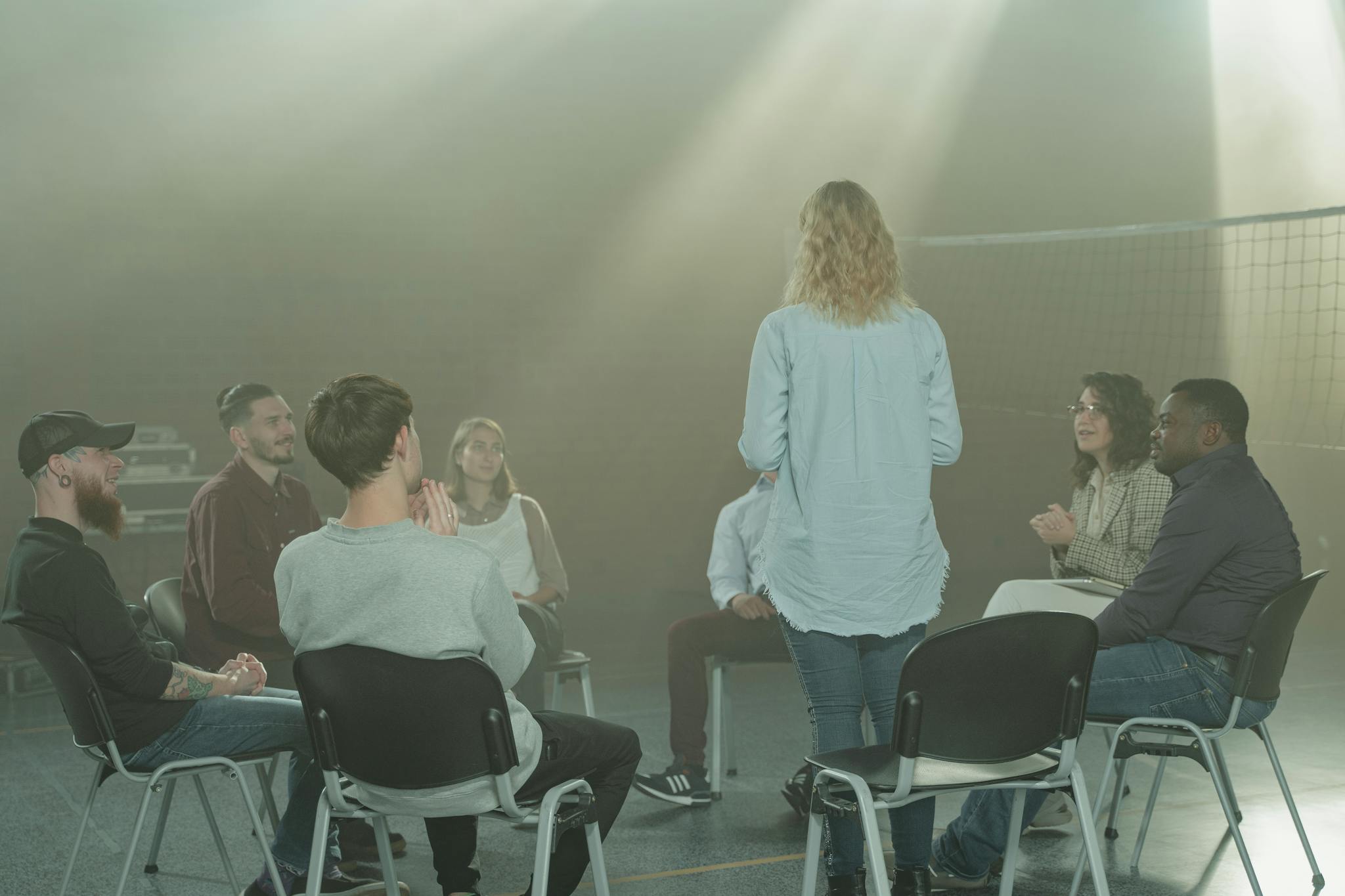 A diverse group in a therapy session indoors with a soft, smoky atmosphere.